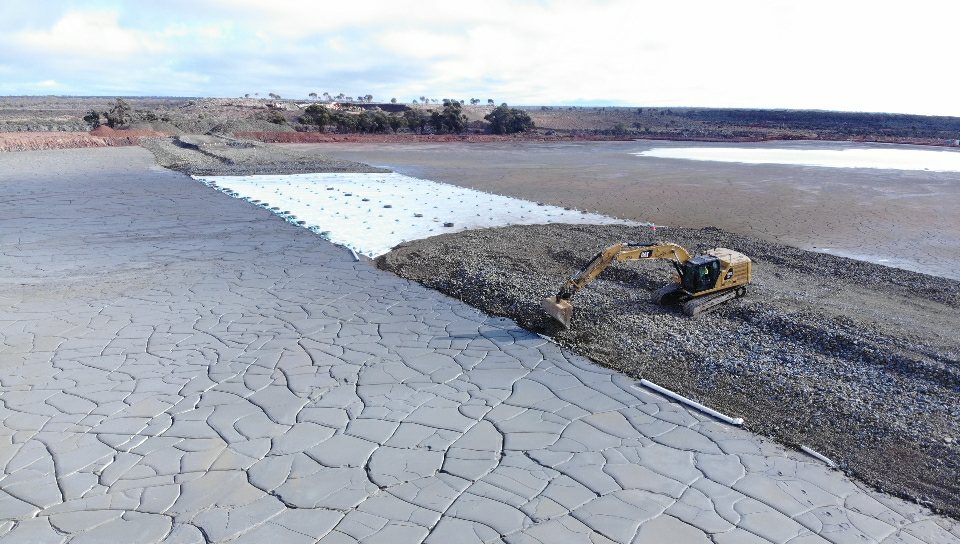 Drone view of tailings rehabilitation with excavator and exposed tailings area